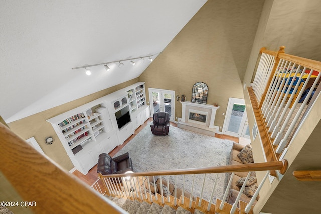 living room featuring a high ceiling, wood finished floors, a high end fireplace, stairs, and track lighting