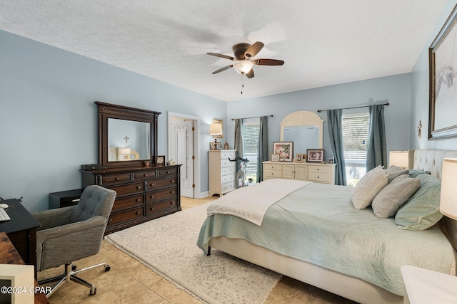 bedroom with a ceiling fan, a textured ceiling, and light tile patterned floors