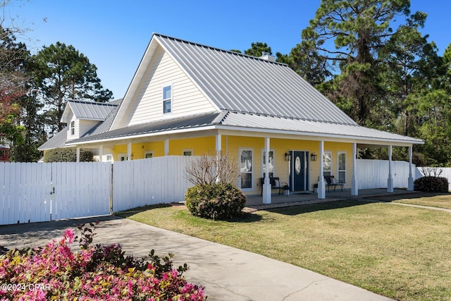 view of front of house featuring metal roof, covered porch, fence, a gate, and a front lawn