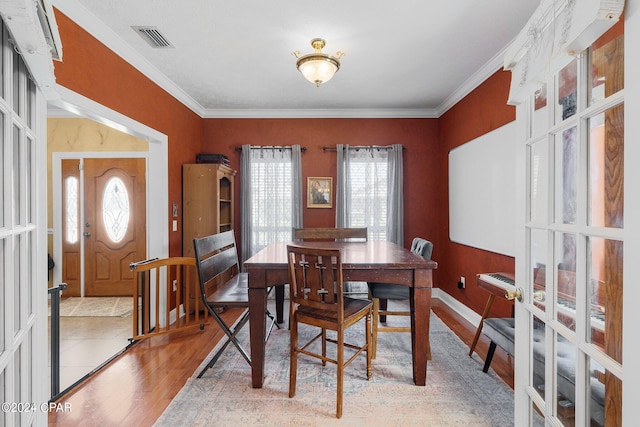 dining space featuring light wood-type flooring, visible vents, crown molding, and baseboards