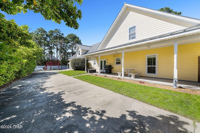 back of property featuring a patio area, fence, metal roof, and a lawn