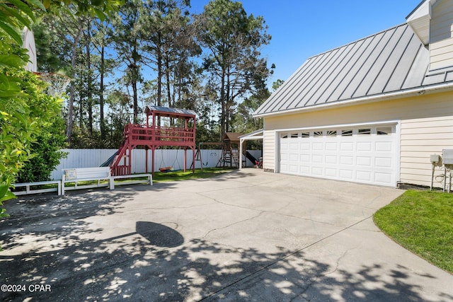 exterior space with a garage, a playground, fence, and driveway