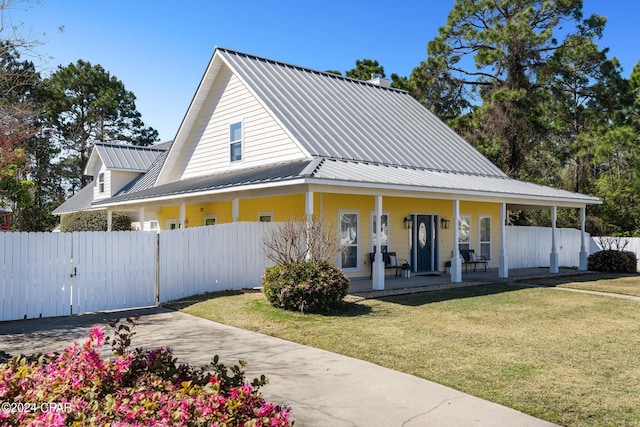 view of front of home featuring metal roof, a porch, fence, a gate, and a front yard