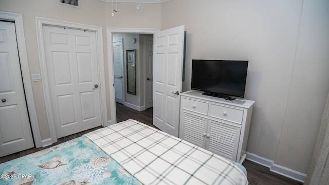 bedroom with visible vents, baseboards, and dark wood finished floors