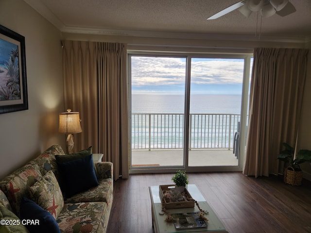 living room featuring hardwood / wood-style floors, ceiling fan, a water view, and a textured ceiling