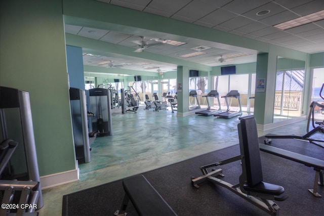 exercise room featuring a drop ceiling, ceiling fan, and baseboards