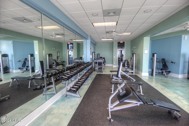 gym with a drop ceiling, ceiling fan, visible vents, and baseboards