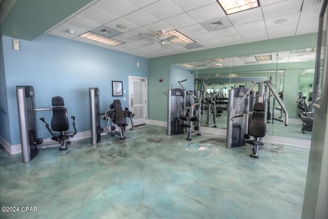 workout area with a drop ceiling, visible vents, and baseboards