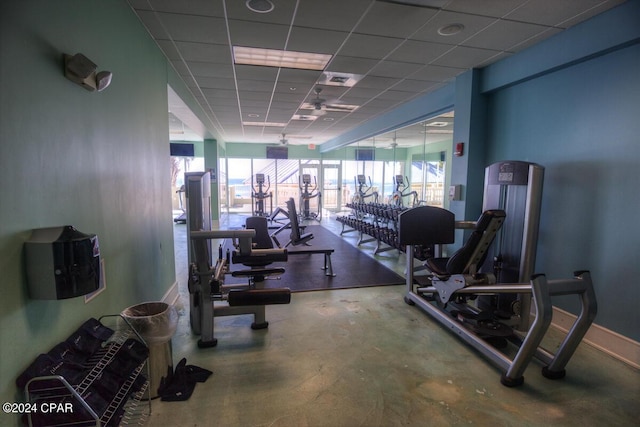 exercise room featuring a paneled ceiling, plenty of natural light, visible vents, and baseboards