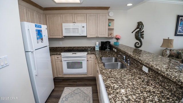 kitchen with white appliances, dark stone counters, dark wood-style floors, a peninsula, and a sink