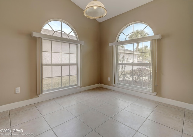 unfurnished room with lofted ceiling, light tile flooring, and a wealth of natural light