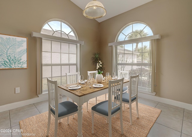 tiled dining area featuring high vaulted ceiling