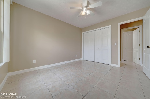 unfurnished bedroom with light tile floors, a closet, and ceiling fan