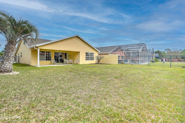 rear view of house with a lawn, a patio, and a lanai