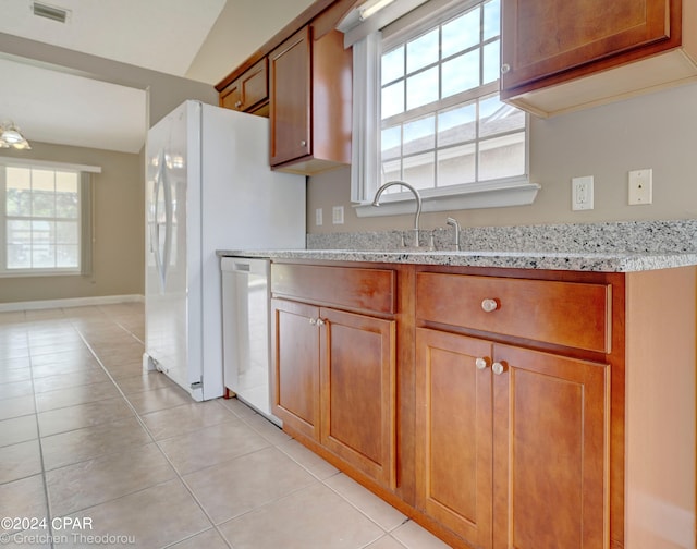 kitchen with light tile flooring, stainless steel dishwasher, light stone countertops, and sink