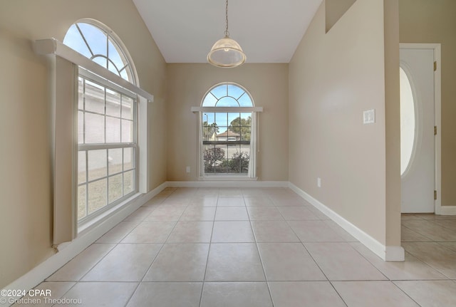 tiled empty room with an inviting chandelier and lofted ceiling