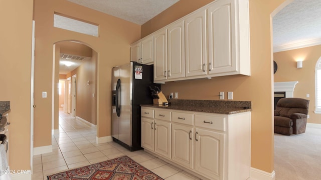 kitchen with light colored carpet, a textured ceiling, white cabinets, dark stone countertops, and stainless steel refrigerator with ice dispenser