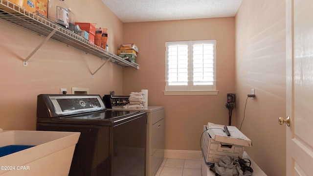 laundry area with sink, a textured ceiling, washer and dryer, and light tile flooring