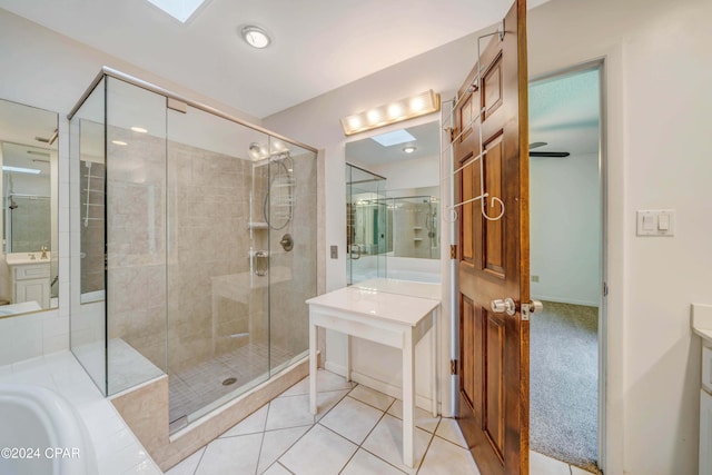 bathroom featuring vanity, a skylight, shower with separate bathtub, and tile patterned floors