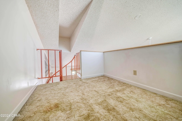 additional living space featuring a textured ceiling and carpet flooring