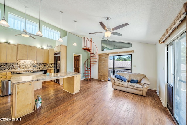 kitchen featuring light stone counters, light brown cabinets, built in refrigerator, a center island, and hardwood / wood-style floors