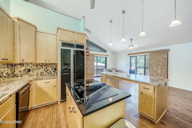 kitchen featuring lofted ceiling, hanging light fixtures, a kitchen island, black appliances, and light brown cabinetry