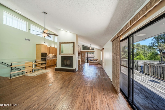 unfurnished living room featuring ceiling fan, a textured ceiling, dark wood-type flooring, and high vaulted ceiling