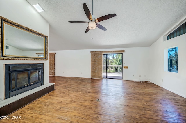 unfurnished living room with wood-type flooring, vaulted ceiling, a textured ceiling, and ceiling fan