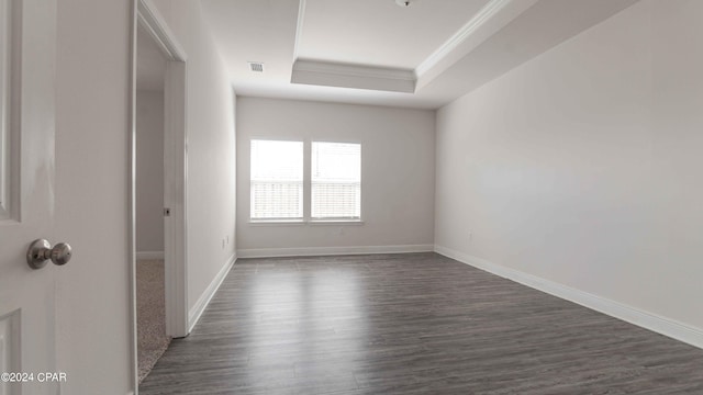 unfurnished room featuring a raised ceiling, ornamental molding, and dark wood-type flooring