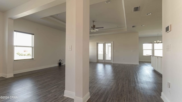 spare room featuring dark hardwood / wood-style floors, a tray ceiling, ornamental molding, ceiling fan with notable chandelier, and french doors