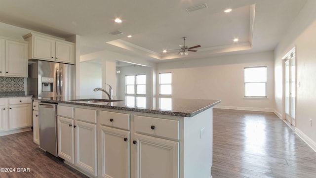 kitchen with white cabinetry, appliances with stainless steel finishes, a raised ceiling, and a center island with sink