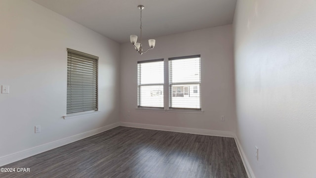 empty room featuring dark wood-type flooring and an inviting chandelier