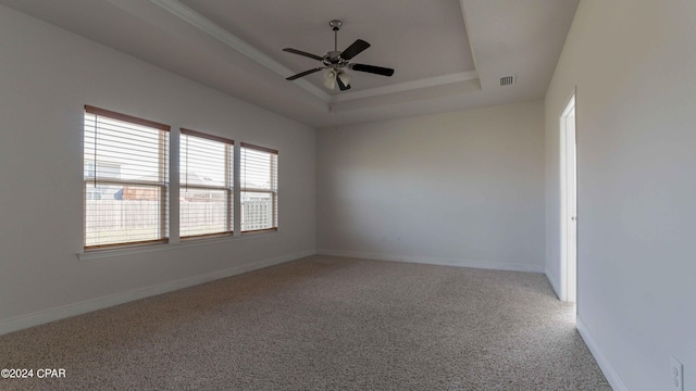 unfurnished room with a raised ceiling, carpet floors, and ceiling fan