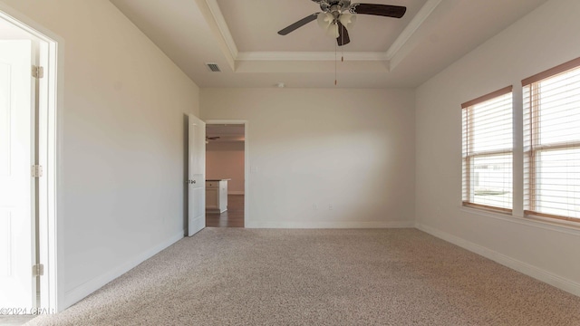 carpeted spare room with ceiling fan and a tray ceiling