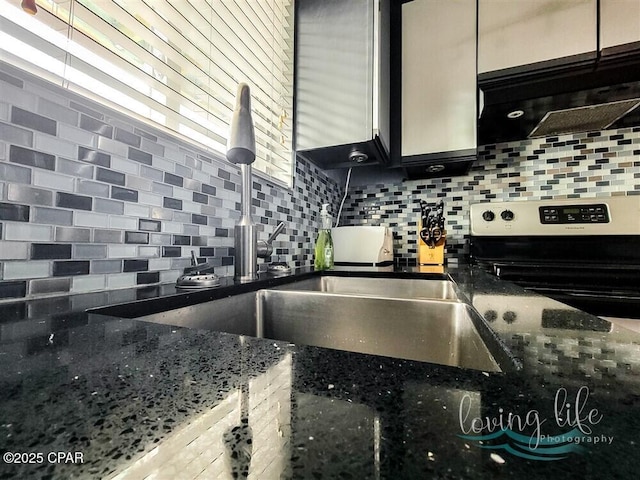 kitchen with decorative backsplash, stainless steel range, and dark stone counters