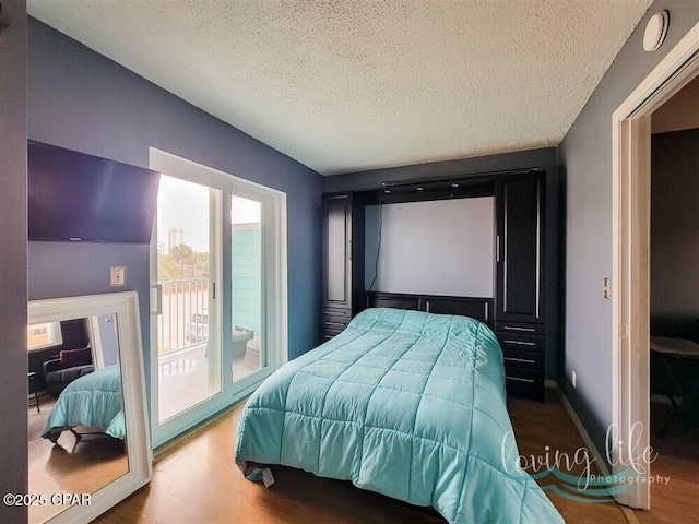 bedroom featuring access to exterior, a textured ceiling, and hardwood / wood-style flooring