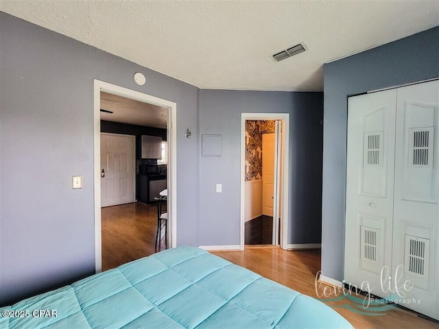 bedroom with a closet, hardwood / wood-style floors, and a textured ceiling