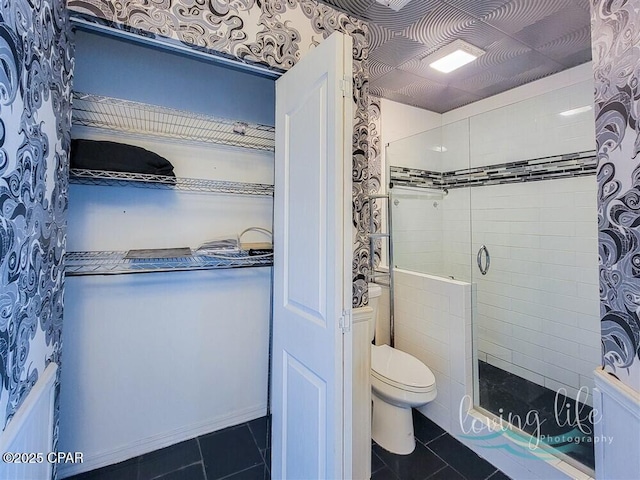 bathroom with tile patterned flooring, toilet, and walk in shower