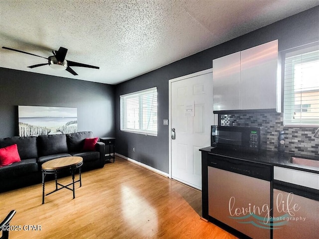 living room featuring a textured ceiling, light wood-type flooring, ceiling fan, and sink