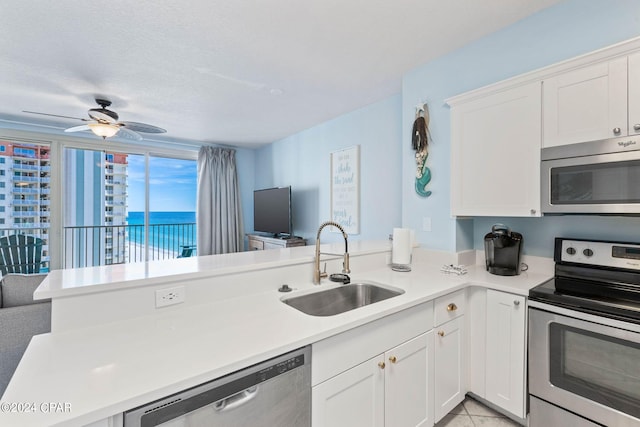 kitchen with kitchen peninsula, ceiling fan, sink, appliances with stainless steel finishes, and white cabinetry