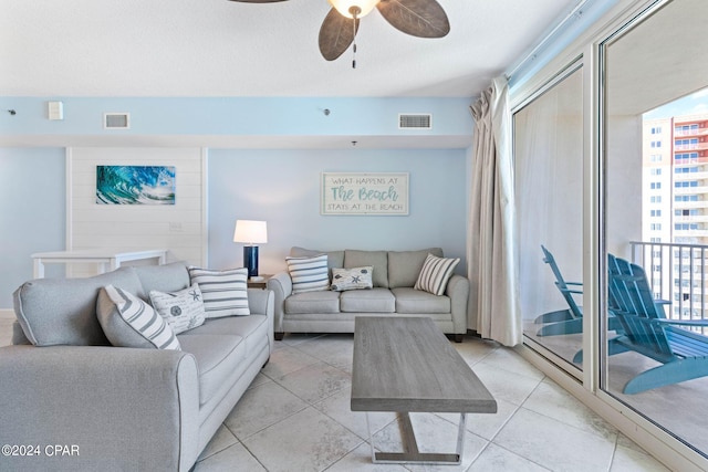 living room featuring light tile floors, ceiling fan, and a textured ceiling