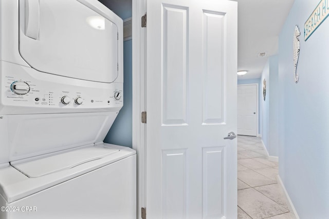 clothes washing area featuring light tile floors and stacked washer / drying machine