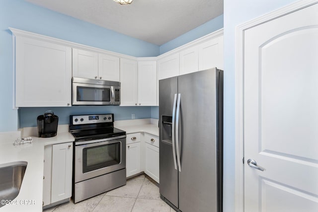 kitchen featuring white cabinets, appliances with stainless steel finishes, and light tile floors