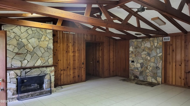 unfurnished living room with wood walls, vaulted ceiling with beams, a fireplace, and light tile patterned floors