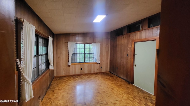 spare room featuring wooden walls and light parquet floors