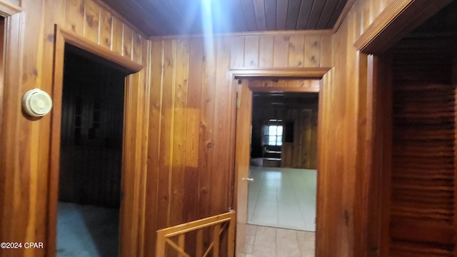 hall featuring wooden walls and tile patterned floors