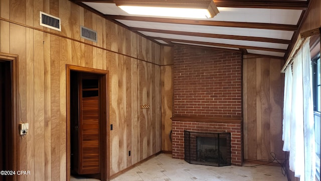 unfurnished living room featuring wood walls, vaulted ceiling with beams, a fireplace, and brick wall