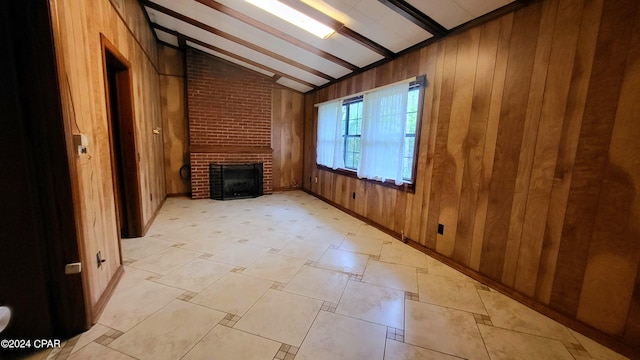 unfurnished living room with light tile patterned flooring, wooden walls, a brick fireplace, lofted ceiling with beams, and brick wall