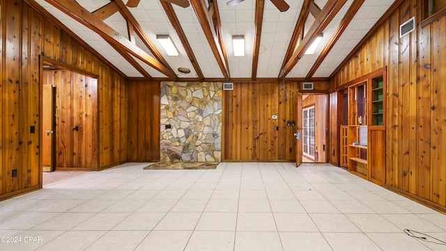 spare room featuring ceiling fan, beam ceiling, wooden walls, light tile patterned flooring, and high vaulted ceiling