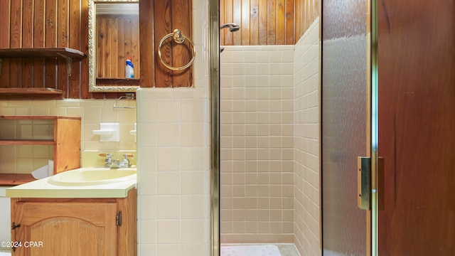 bathroom with tasteful backsplash, tile walls, walk in shower, and vanity